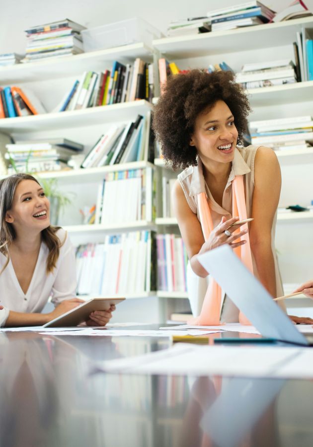 A diverse team smiling and talking around a table in a bright office.