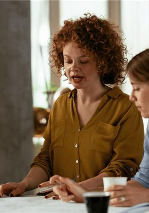 Three coworkers discussing documents together at a workspace with coffee cups.